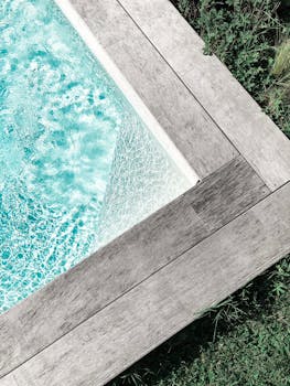 特写镜头下，一个宁静的游泳池被木制甲板环绕，四周绿意盎然