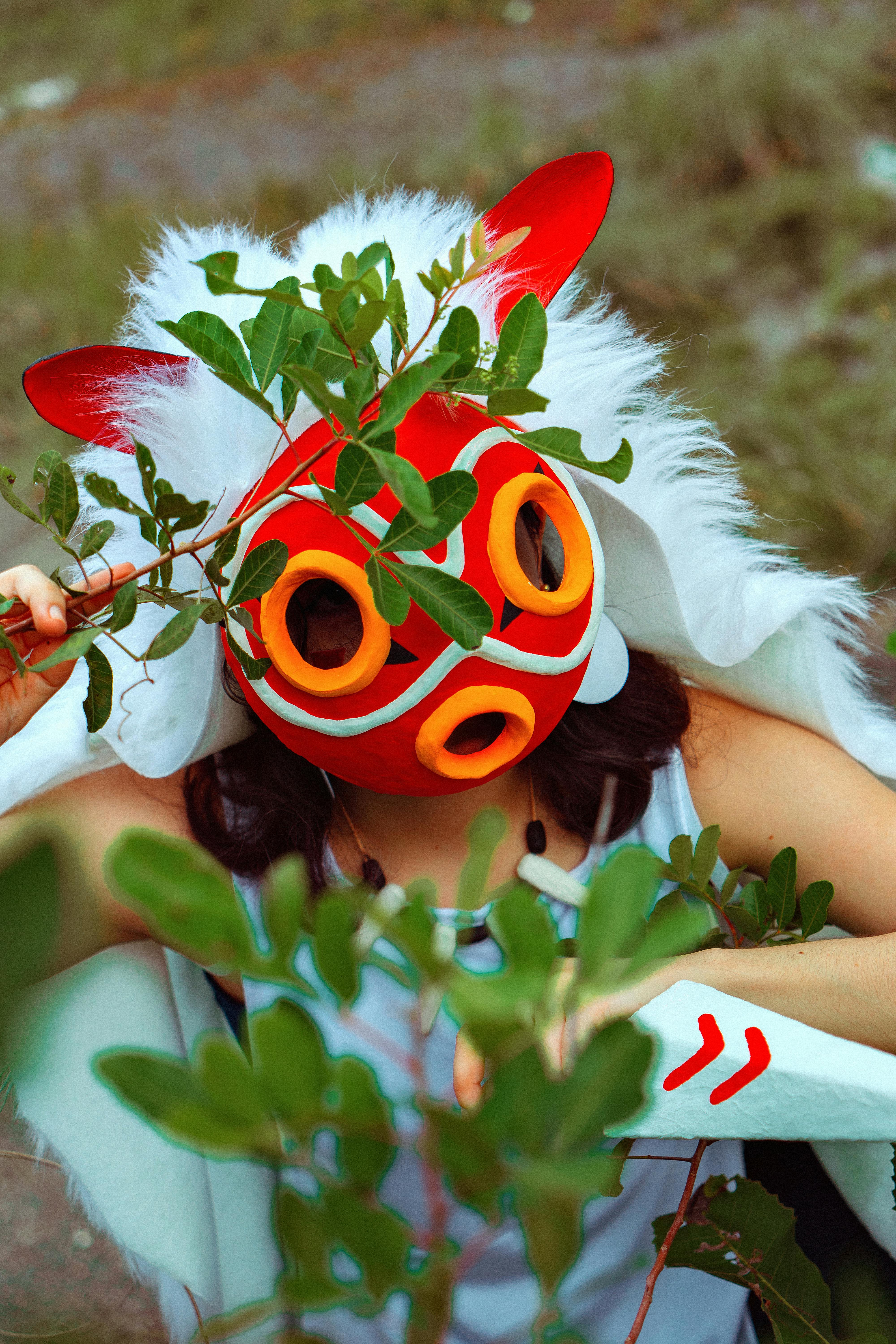 vibrant cosplay portrait with red mask and foliage