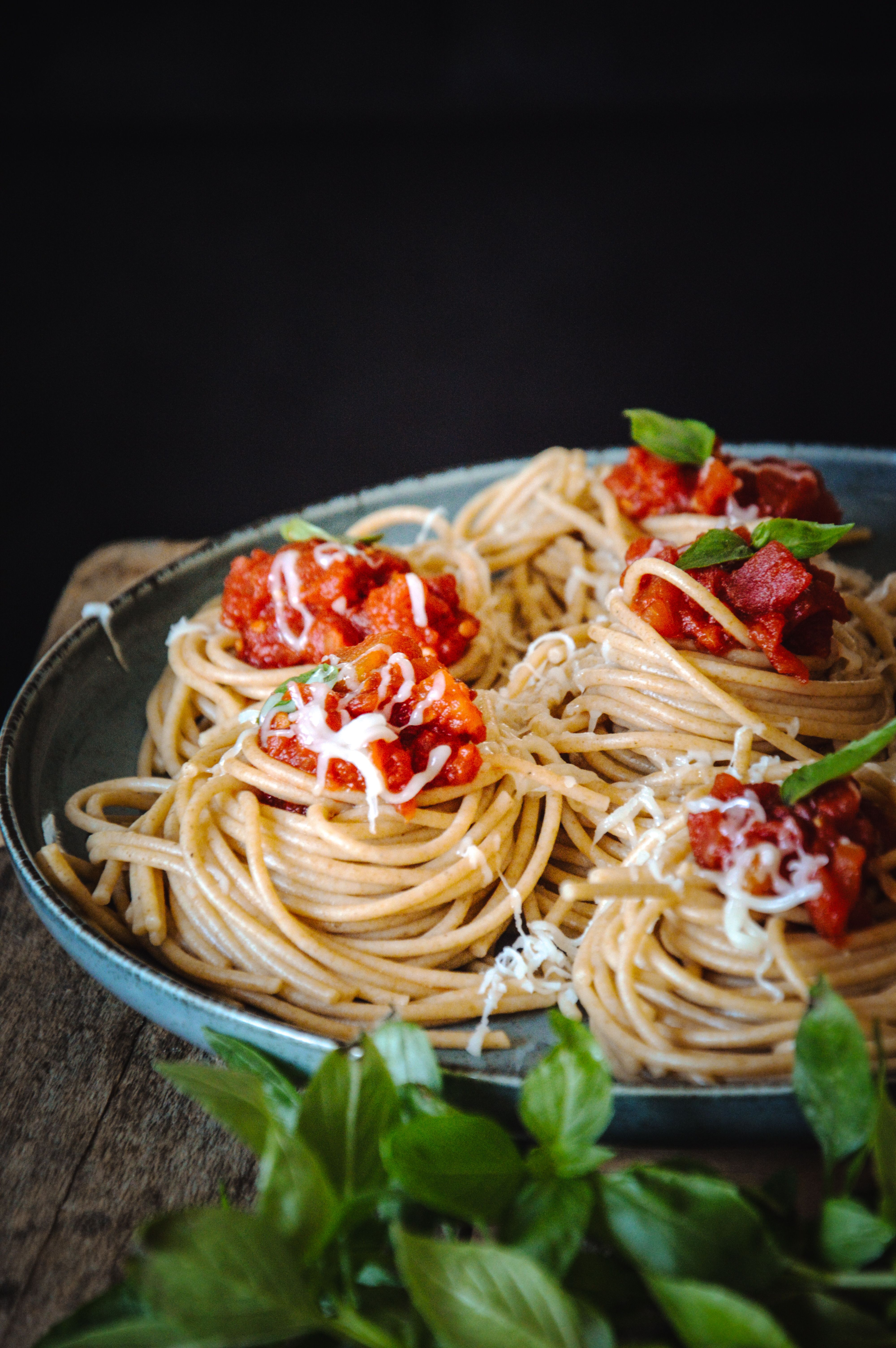 A plate of whole wheat spaghetti topped with marinara sauce and fresh basil.