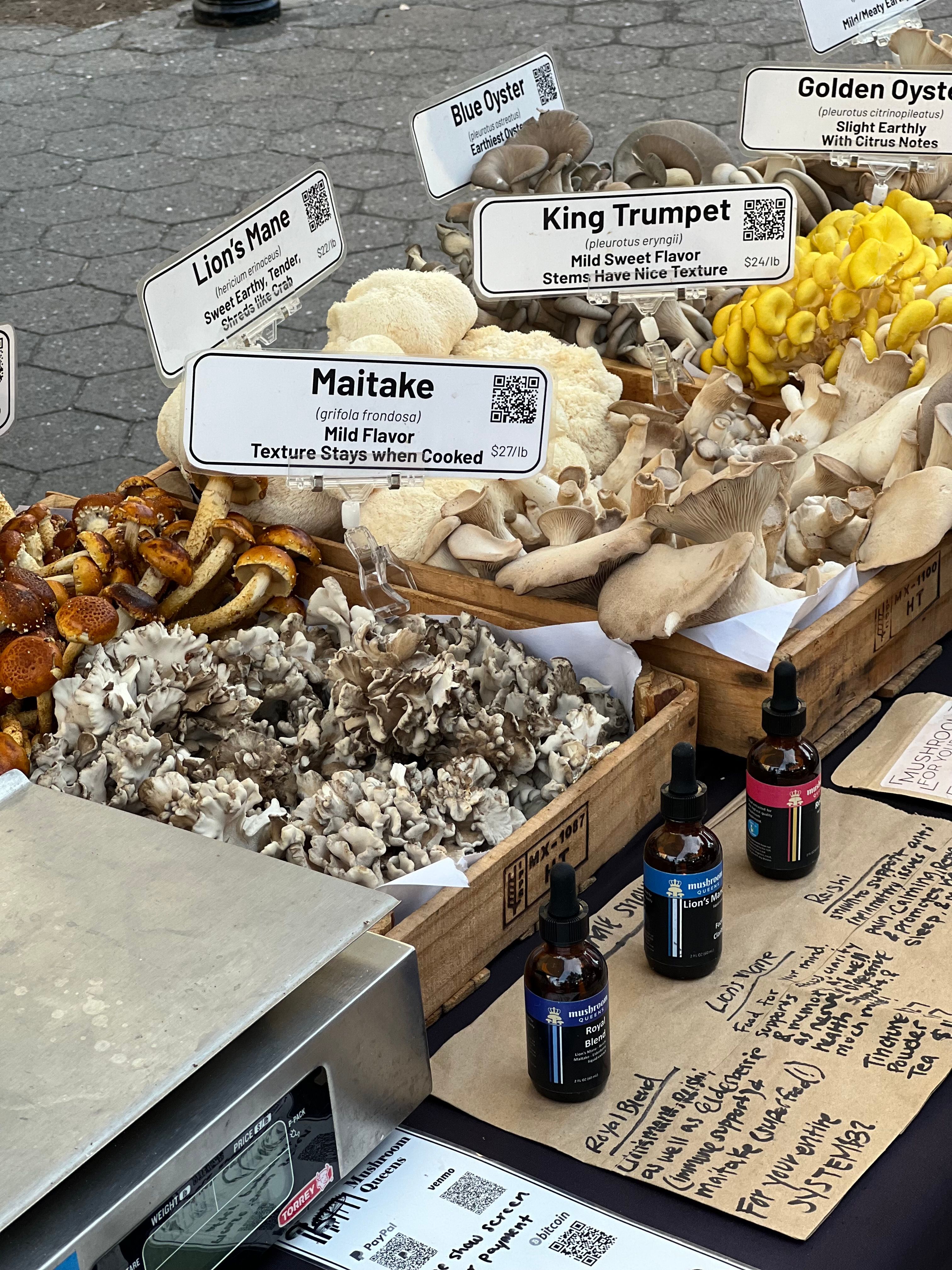 Fresh maitake mushrooms displayed with a label at a produce market
