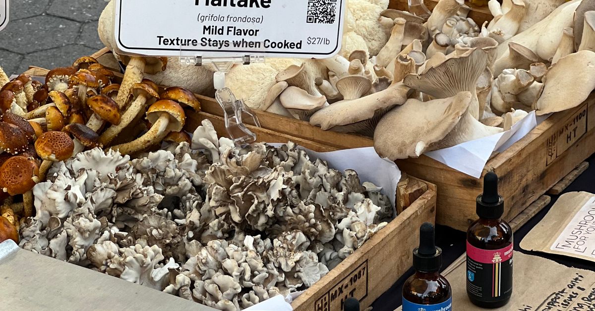 Fresh maitake mushrooms displayed with a label at a produce market