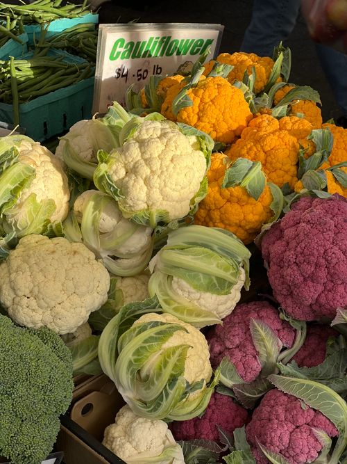 Free Variety of colorful cauliflower heads displayed at a market. Stock Photo