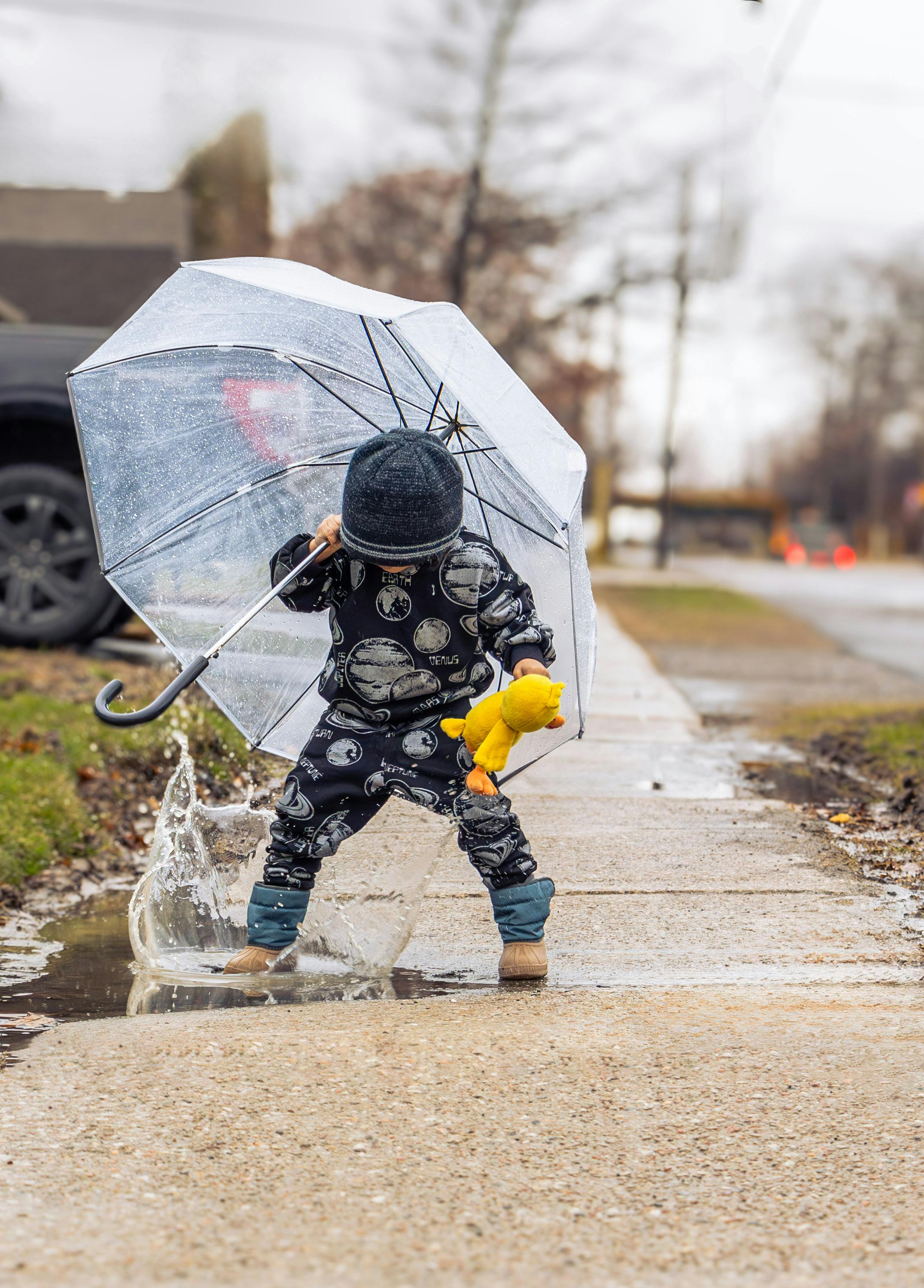 child playing in rain with umbrella