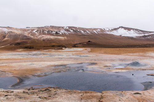 Free A captivating geothermal landscape in Iceland featuring steaming pools and snow-capped mountains in the background. Stock Photo