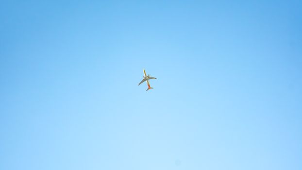 A passenger airplane flying high in a clear blue sky, showcasing minimalist photography.