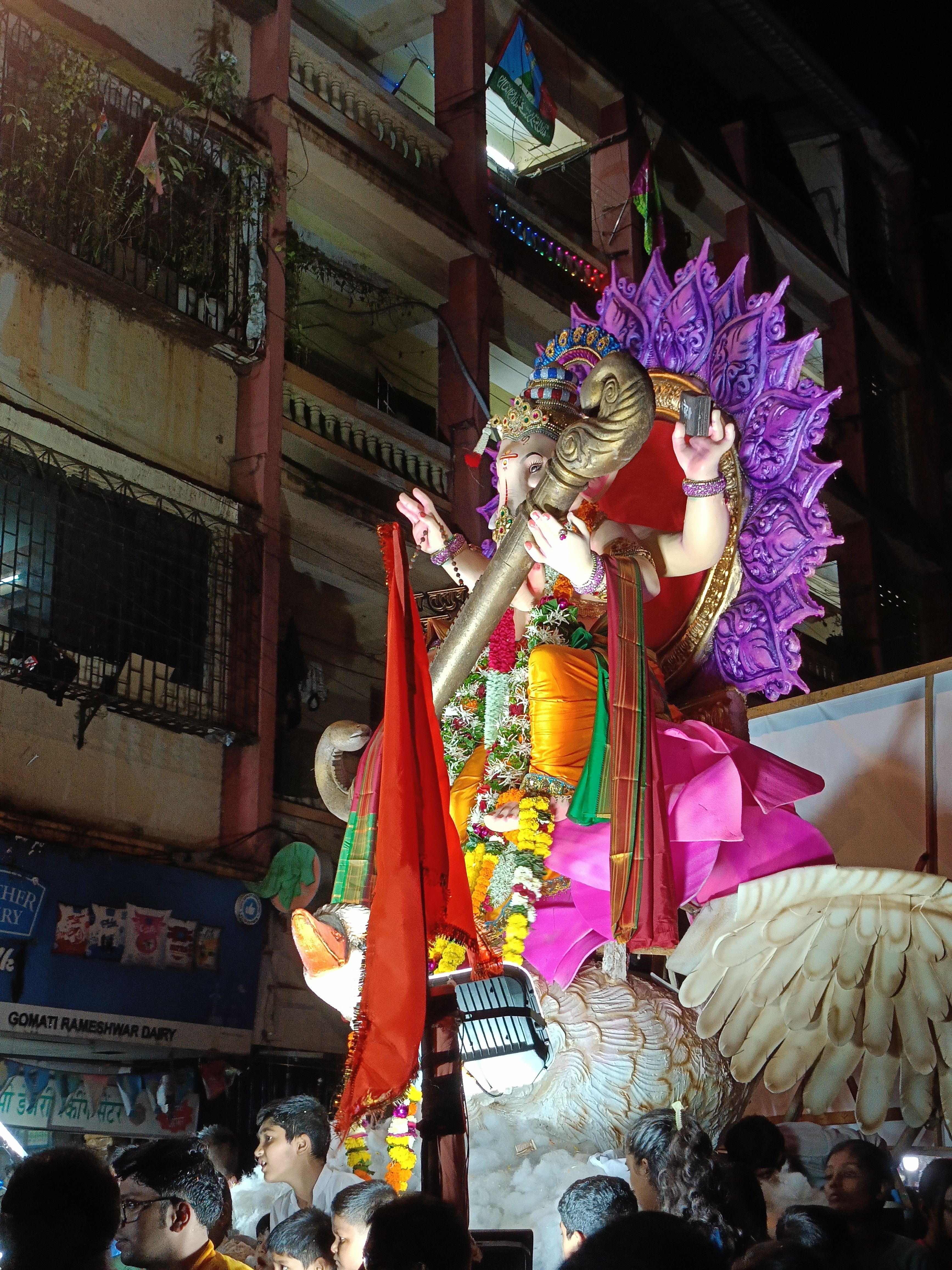 Vibrant Ganesh idol procession during Ganesh Chaturthi in Mumbai, India at night.