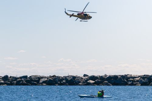 Free Kayaker watches a helicopter fly over Lake Ontario with Toronto skyline nearby. Bright summer day. Stock Photo