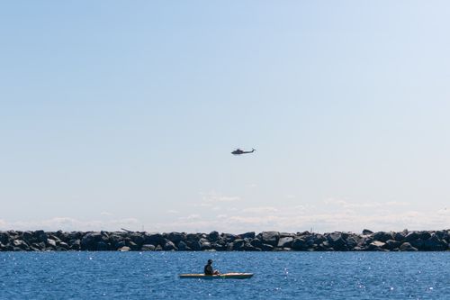 Free Person kayaking on Lake Ontario with a helicopter flying above, clear sky, Toronto. Stock Photo