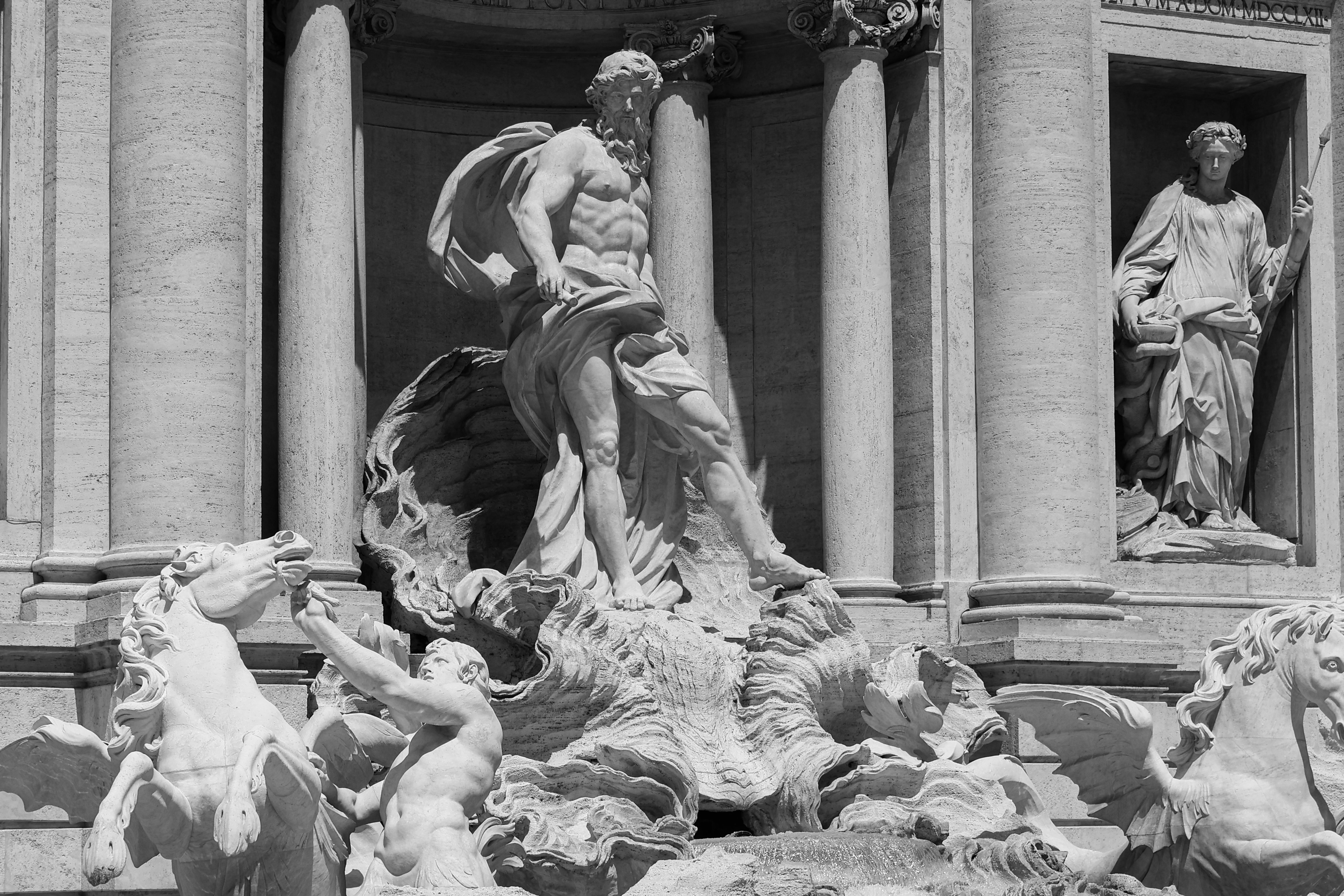 Black and white photo of Neptune's statue at Trevi Fountain, Rome, showcasing classic Italian craftsmanship.