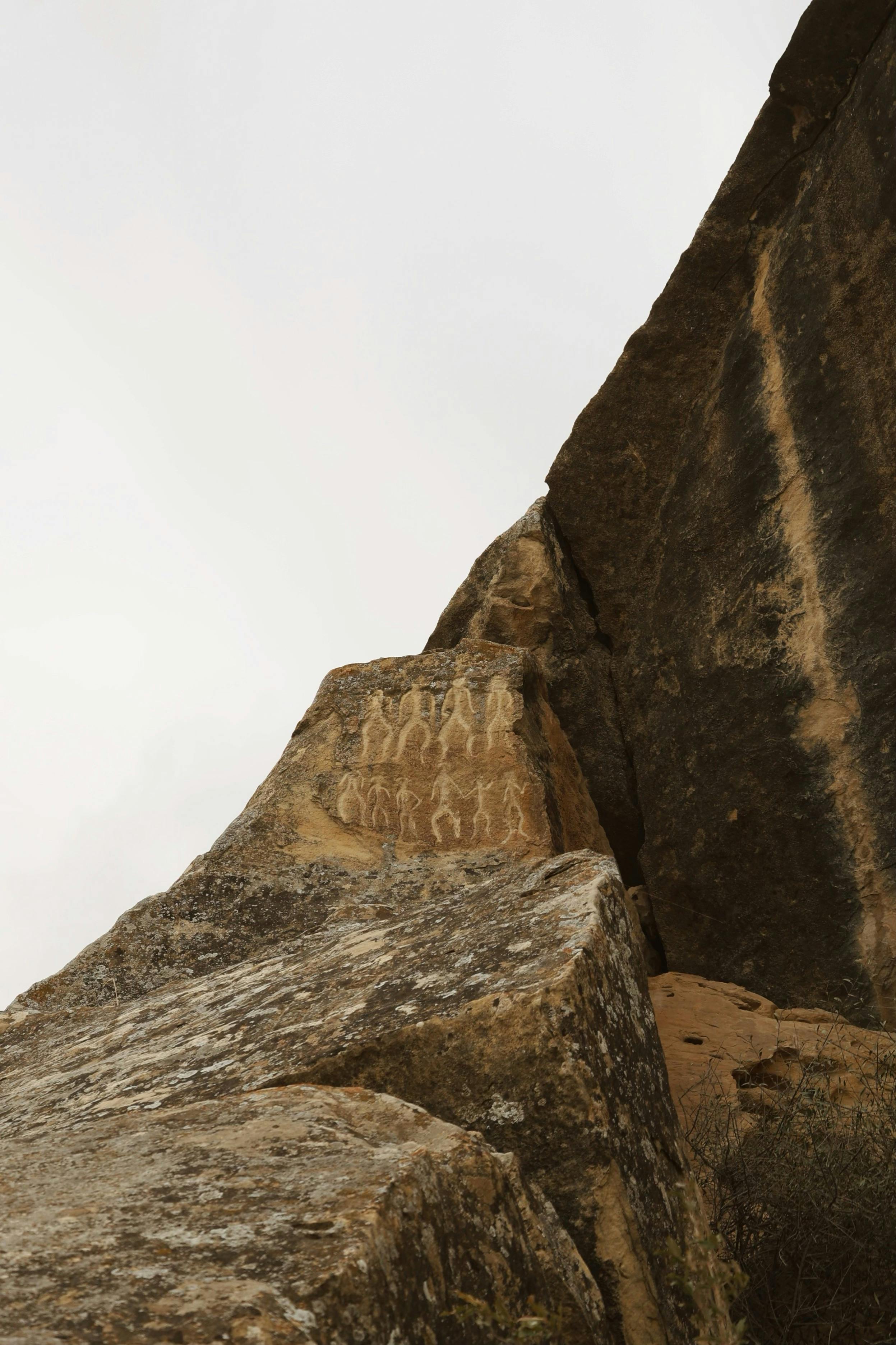 Explore ancient petroglyphs etched on a rocky cliff in a barren landscape.