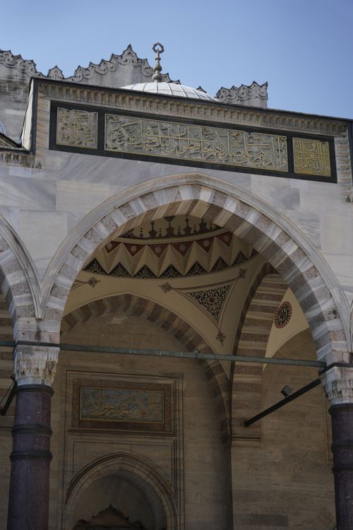 Free Detail of an ornate Islamic arch with intricate Arabic calligraphy and geometric patterns observed on a sunny day. Stock Photo