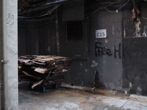 Free A gritty Hong Kong alleyway with stacked cardboard and graffiti on dark walls, showcasing urban life. Stock Photo