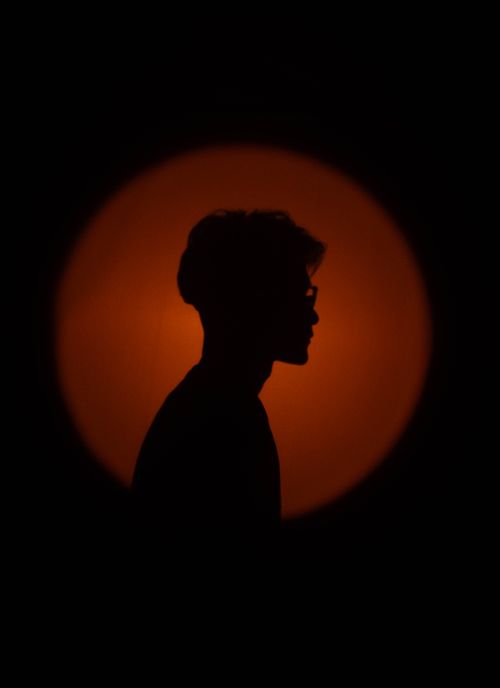 Free Artistic silhouette of a person with an orange circular glow, creating a dramatic visual impact. Stock Photo