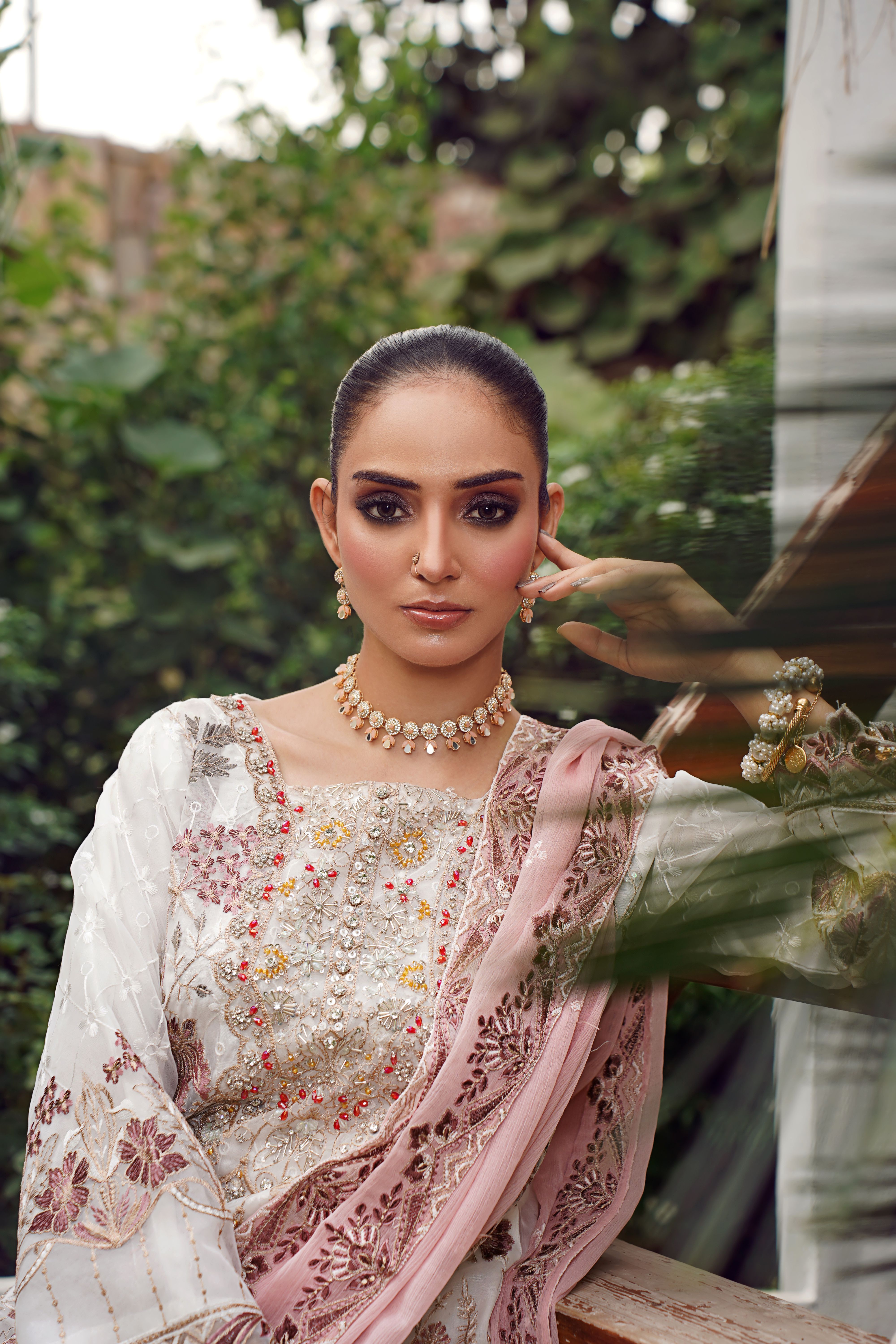 Stunning portrait of a model in traditional attire captured in a lush Lahore garden.