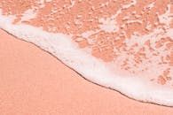 粉红色的沙滩特写，柔和的海泡沫侵蚀了海岸，营造出宁静的沿海风光