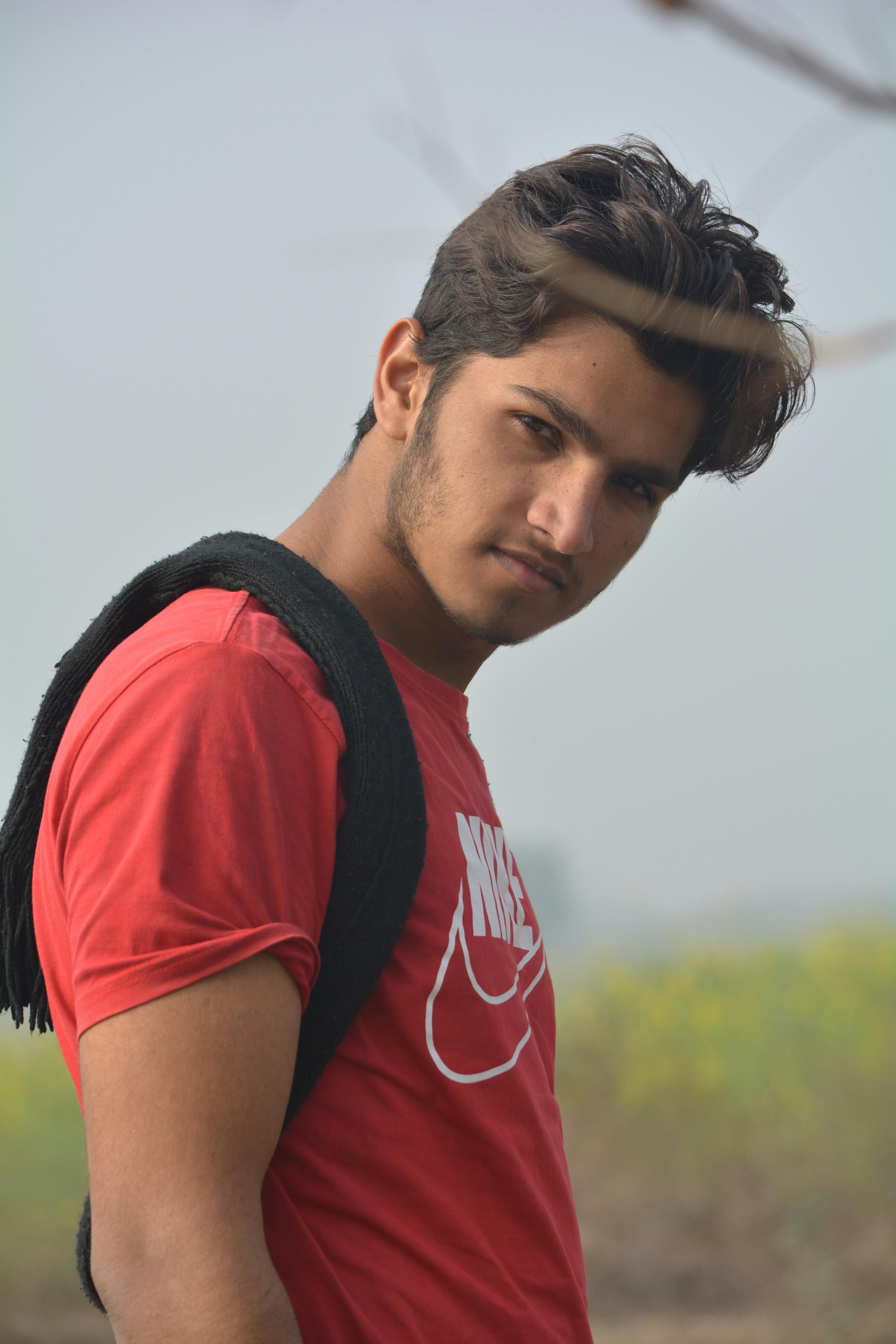 Casual portrait of a young man wearing a red Nike shirt outdoors.
