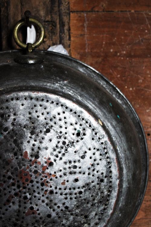 Free Close-up of a classic metal colander on a rustic wooden surface, showcasing textures and patina. Stock Photo