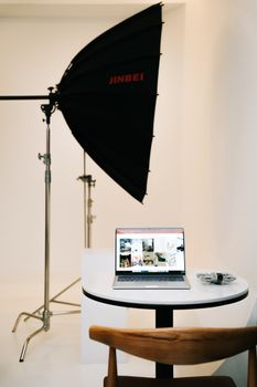 Studio setup featuring a softbox light and a laptop for photo editing, creating a clean and professional workspace.