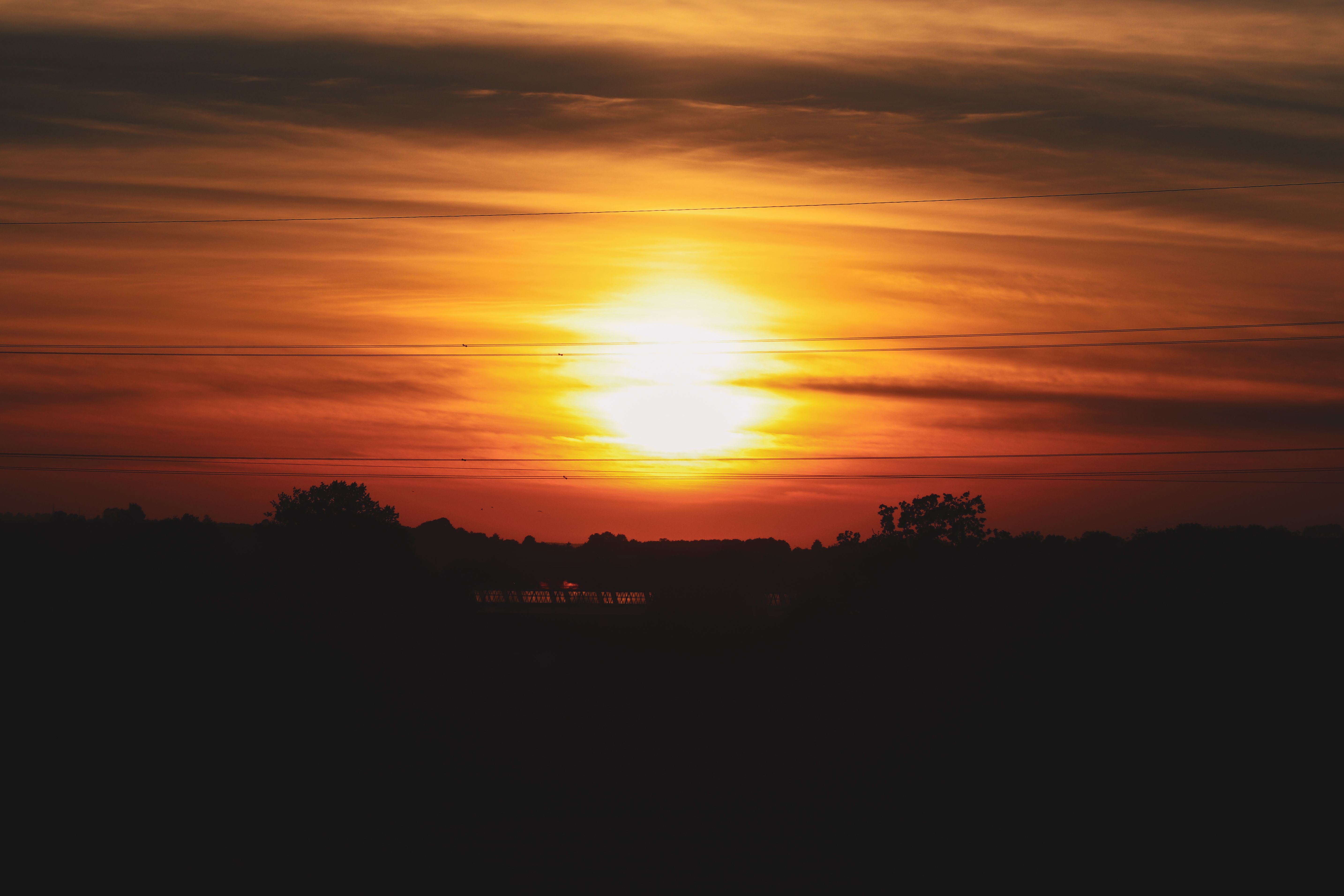 Beautiful sunset with vibrant orange hues over a dark silhouetted horizon.