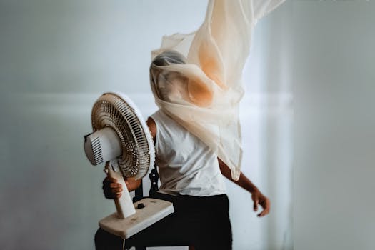 Creative artistic portrait of a person with a veil, interacting with an electric fan indoors.
