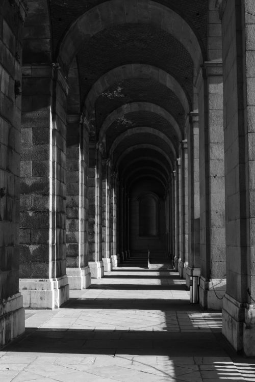 Free Dramatic black and white photo of Madrid's historic stone arches highlighting light and shadow. Stock Photo