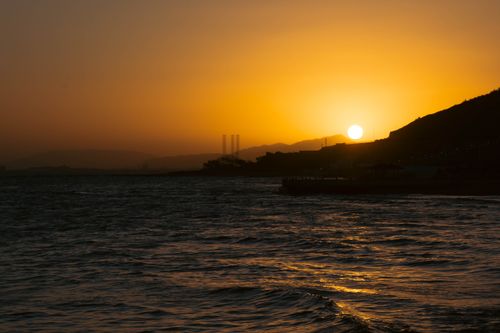 Free Stunning sunset scene with golden hues casting over ocean waves. Stock Photo