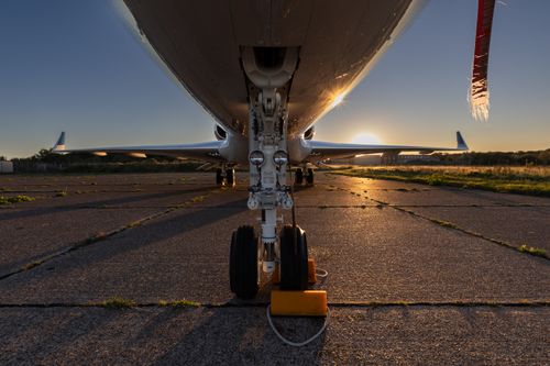 Free Close-up of airplane landing gear during sunset on an empty runway, highlighting travel and aviation themes. Stock Photo
