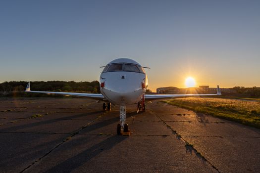 A private jet parked on the runway during a stunning sunset, highlighting the serene aviation scene.