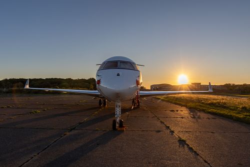 Free A private jet parked on the runway during a stunning sunset, highlighting the serene aviation scene. Stock Photo