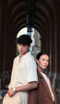 Stylish couple poses under a dramatic archway, blending fashion with architecture.