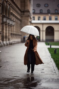 Woman with umbrella walking in a city during rain. Stylish brown coat and elegant setting.