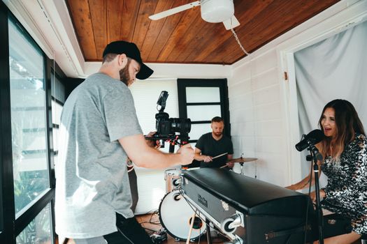 Camera crew capturing a music video performance indoors with singers and musicians.