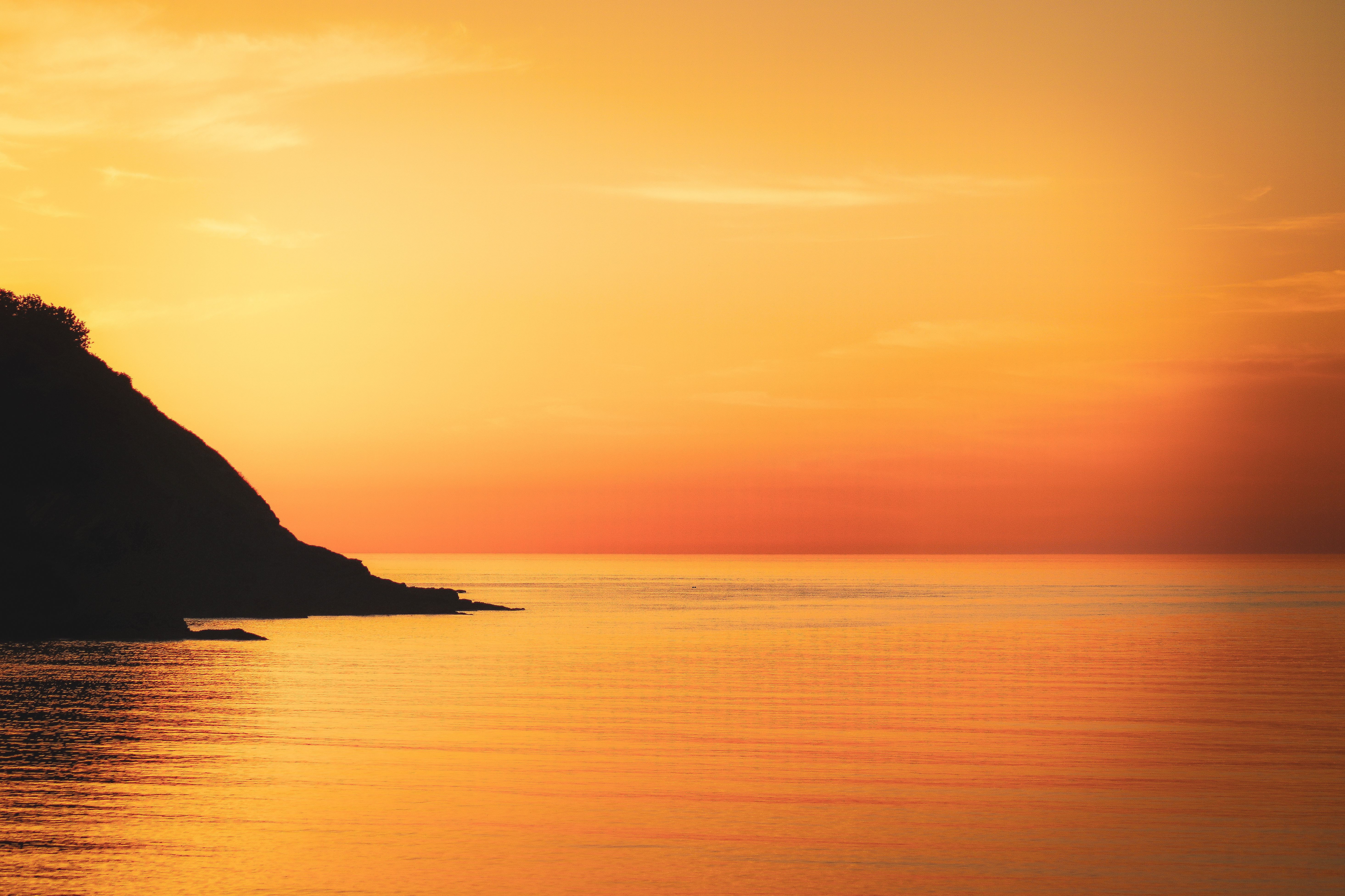 golden sunset over ocean coastal cliffs dreamy cinematic orange and pink sky