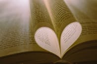 在温暖的灯光下，书页形成的创意心形象征着对阅读的热爱