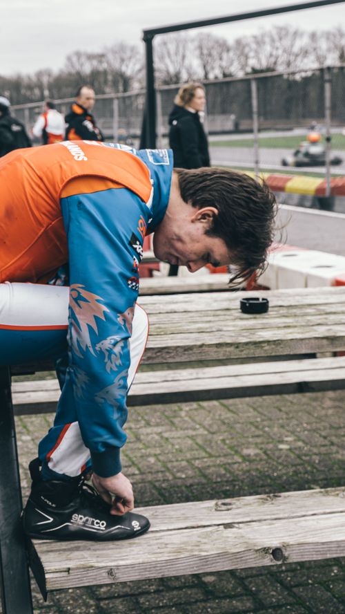 Free A kart racer ties shoes at the Berghem track. Racing gear and equipment in focus. Stock Photo