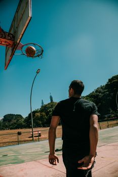 Dynamic basketball shot captured at a local court in Brasília, Brazil, under clear blue skies.