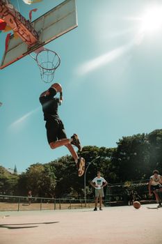 Energetic basketball player performs a dunk under the sunny sky in Brasília, Brazil.
