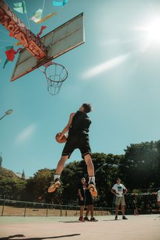 Energetic street basketball scene in Brasília capturing a thrilling dunk against a clear blue sky.