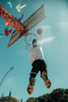 Low angle shot of a basketball player dunking under a clear Brasília sky.