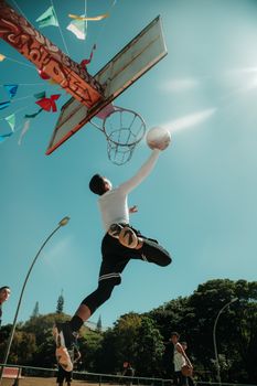 A dynamic low-angle shot of a male basketball player dunking under a clear blue sky in Brasília.