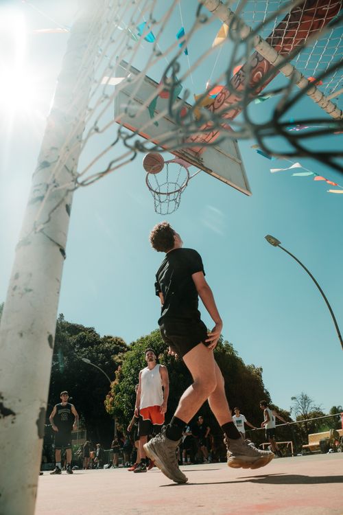 Free Young adults playing basketball under a sunny sky in Brasília, DF, Brazil. Stock Photo