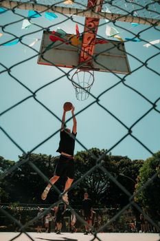 Dynamic basketball scene with players performing a dunk on an outdoor court in Brasília.