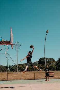 Male basketball player performing a dunk on an outdoor court in Brasília, Brazil.