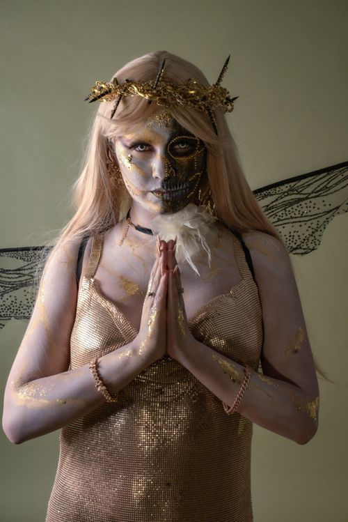 Free Ethereal figure with intricate face paint, adorned in gold and angelic wings, exuding a mysterious aura. Stock Photo