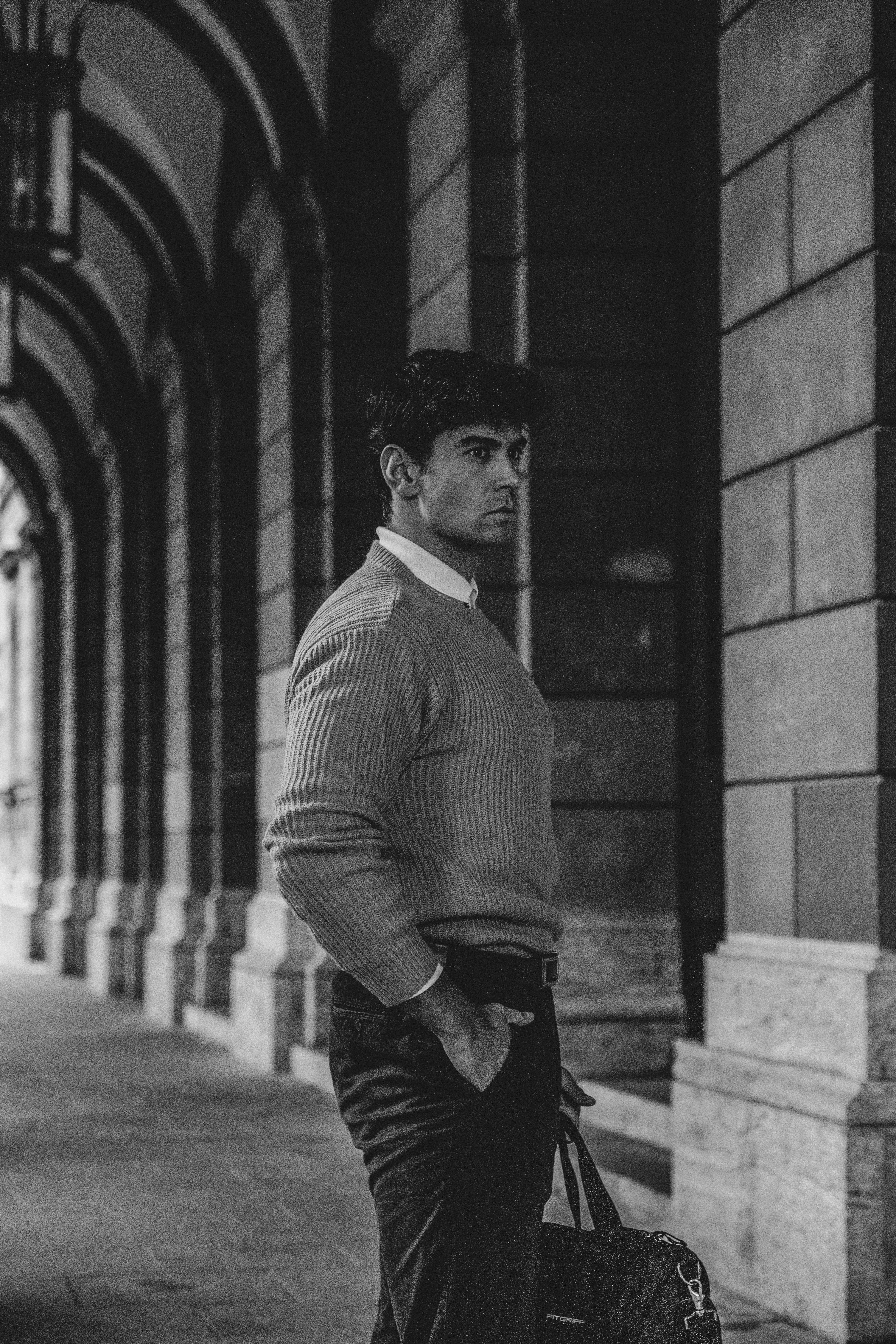 Elegant black and white photo of a man under a city colonnade.