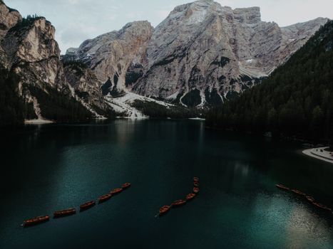 Stunning view of wooden boats on an alpine lake surrounded by majestic Dolomite mountains.