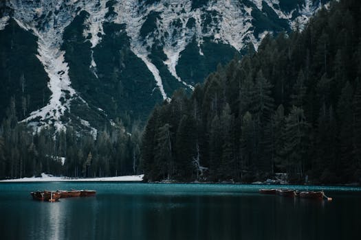Tranquil alpine lake with floating wooden boats and dense forest backdrop.