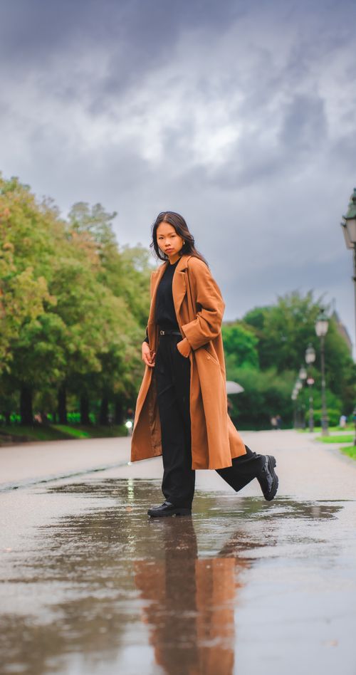 Free Stylish woman in Munich reflects calm beside rain puddles, showcasing modern fashion. Stock Photo