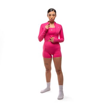 Confident woman in vibrant pink sportswear standing against a white backdrop, showcasing athletic style.