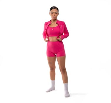Confident woman in pink sportswear against a white background, embodying fitness and style.